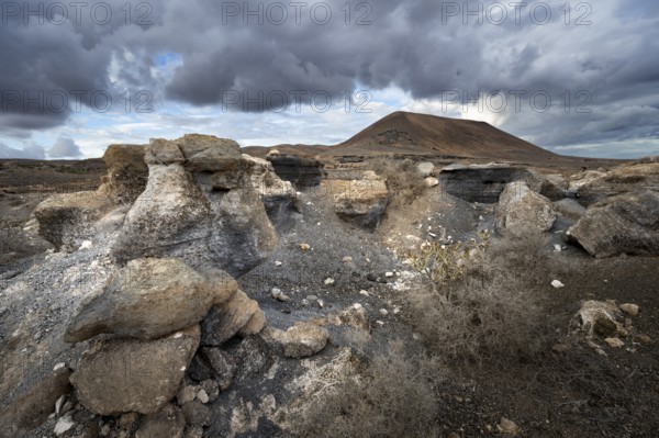 Eroded rock formations in volcanic landscape with dramatic cloudy skies, Ciudad Estratificada or