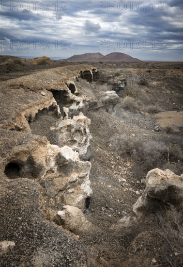 Eroded rock formations in volcanic landscape with dramatic cloudy skies, Ciudad Estratificada or
