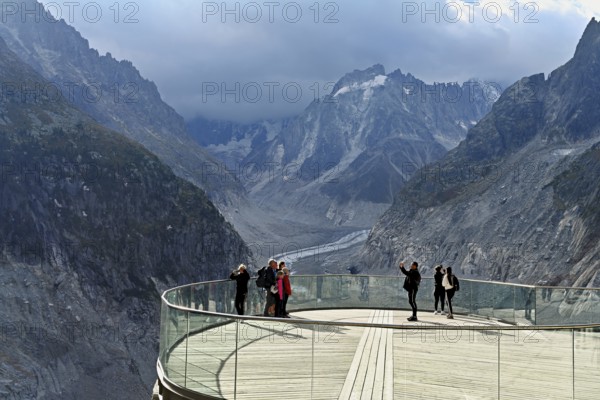 A group of people take pictures of themselves on the viewing platform in front of the Mer de Glace