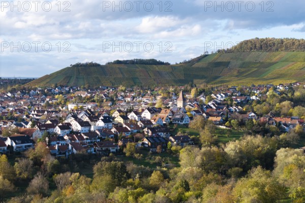 View of a village with church between vineyards and hills under a cloudy sky, autumn,