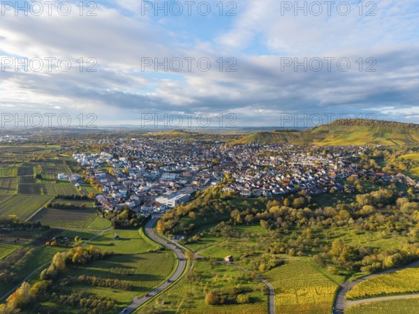 Aerial view of a village surrounded by hills and vineyards under cloudy sky, autumn,