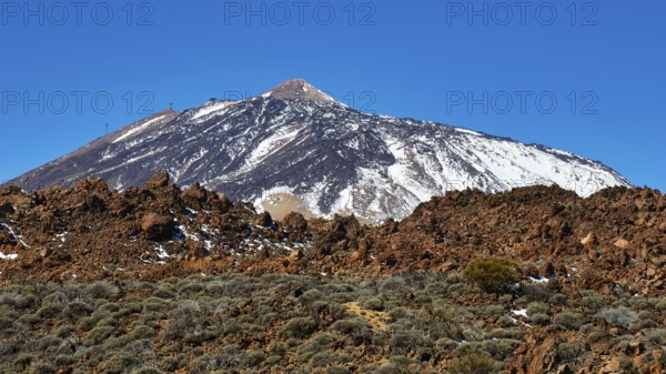 Snow-capped Teide volcano against barren rocky landscape under clear sky, UNESCO World Heritage