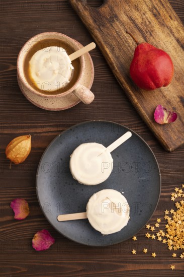 ?hocolate Ice cream in white glaze, cup of coffee, on brown wooden background, top view, flat lay,