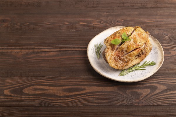 Fried Turkey Thigh with spices and rosemary on plate on brown wooden background. side view, copy