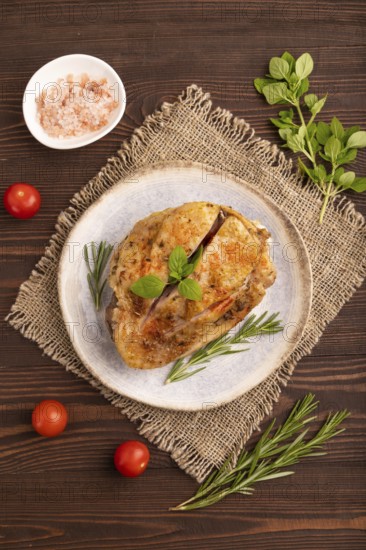 Fried Turkey Thigh with spices and rosemary on plate on brown wooden background and linen textile.
