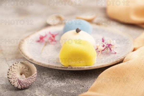 Japanese Mochi Cakes on brown concrete background and orange textile, side view, close up,