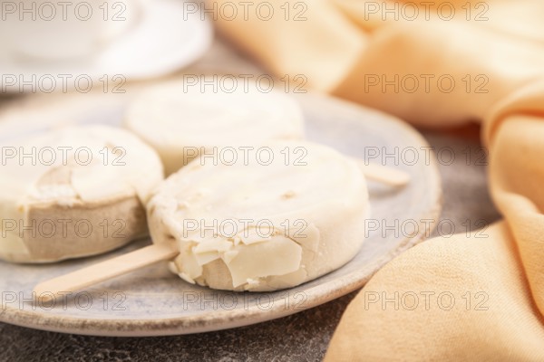 ?hocolate Ice cream in white glaze, cup of coffee, on brown concrete background and orange textile,
