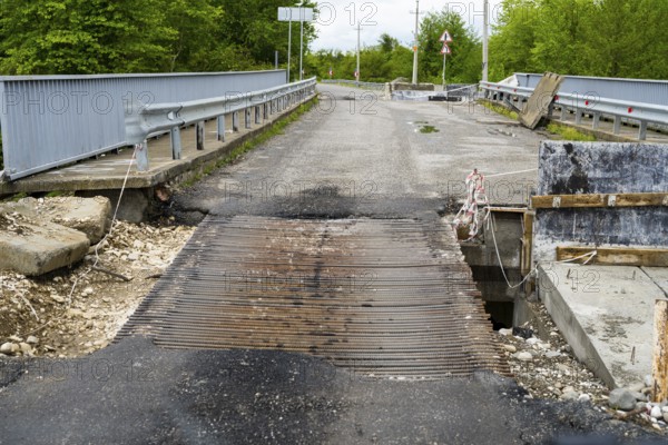 Damaged bridge with metal mesh and surrounding construction in a green area, bridge over the