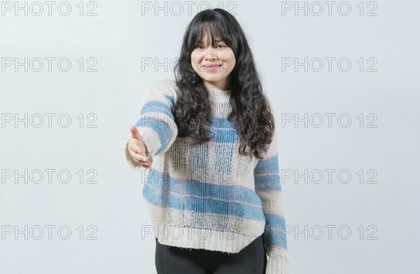 Attractive Asian girl greets you with open hand isolated. Cheerful woman extending her hand to the