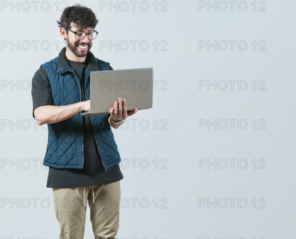 Portrait of Bearded guy using and looking laptop isolated. Handsome young man with glasses holding