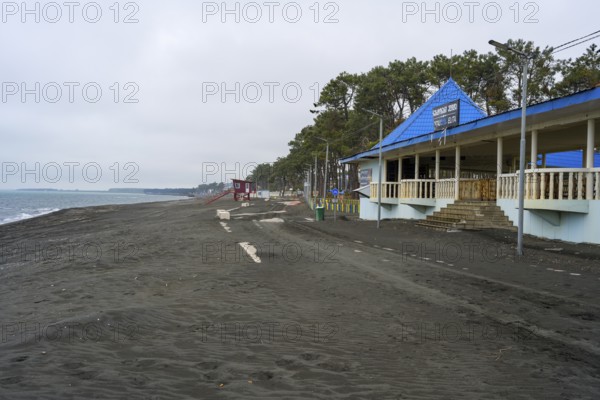 Promenade with buildings and trees along a cloudy beach, beach with magnetic sand, magnetite,