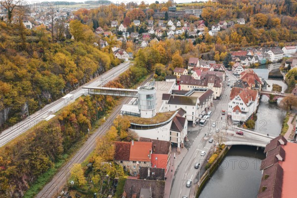 Idyllic small town in autumn colors with a river and bridge, surrounded by colorful trees. Railway