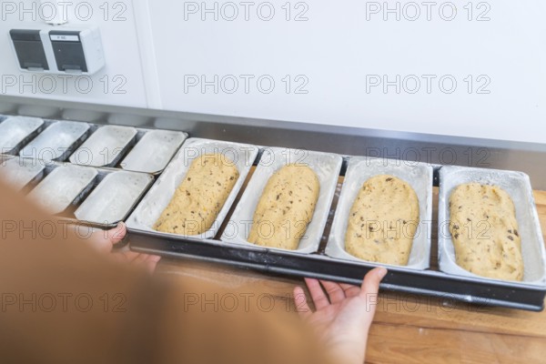 Baker prepares dough in metal box molds on a wooden board in a kitchen, Christmas baking,
