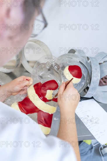 Person paints a Santa Claus mold with red and white tint, Christmas baking, Haselstaller Hof,
