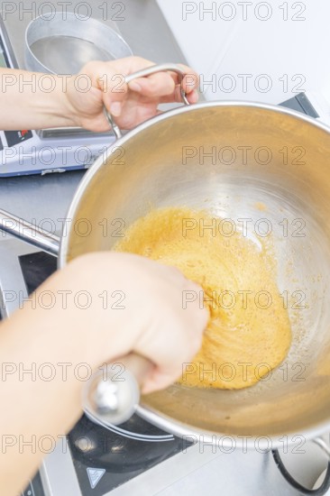 A person is stirring a yellow dough in a pan on a stove, Christmas baking, Haselstaller Hof,