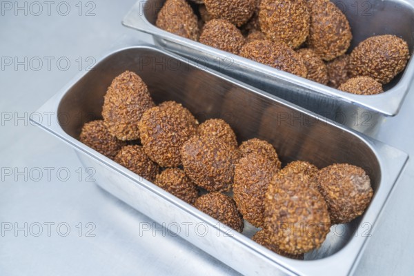 Metal container full of chocolate-coated balls in a professional kitchen, Christmas baking,