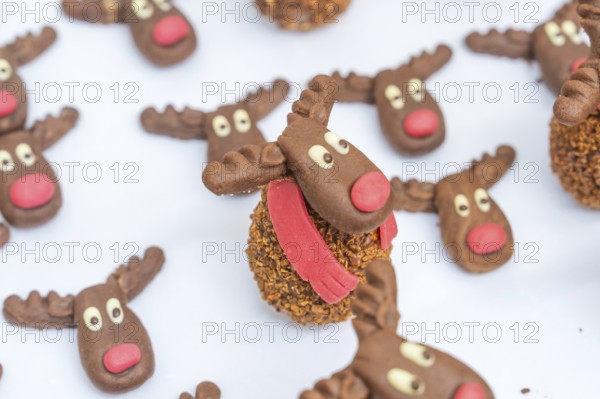 Reindeer chocolate chip cookies with red noses and white eyes, presented on a white background,