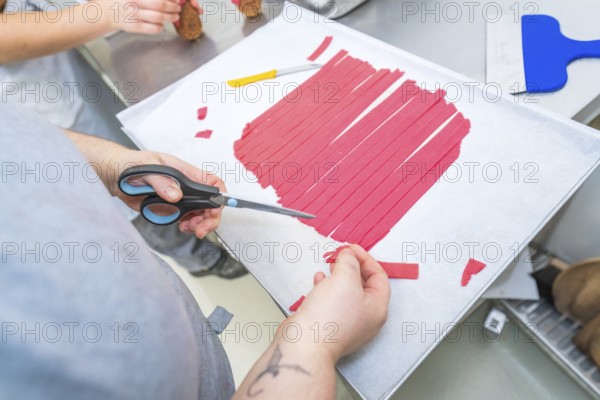 Red strips are cut with scissors on a baking sheet, Weihnachtsbacken, Haselstaller Hof, Wildberg,