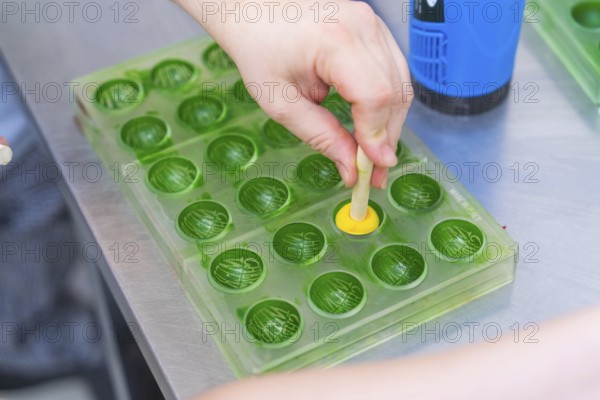 A hand forms a praline in a green chocolate mold, Christmas baking, Haselstaller Hof, Wildberg,