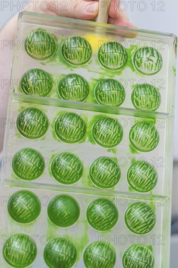 Green chocolate mold with the text 'Merry Christmas' in a chocolate workshop, Weihnachtsbacken,