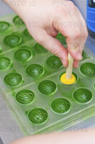 A hand shapes a yellow chocolate with a green chocolate mold, Christmas baking, Haselstaller Hof,