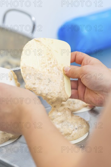 Dough is held by one hand with a silicone spatula and poured into a mold, Weihnachtsbacken,