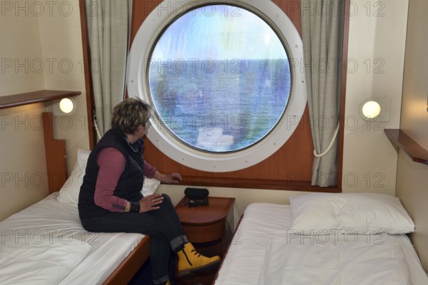 Woman looking out of her ship cabin at the sea, Baltic Sea, Color Line ferry, Schleswig-Holstein,