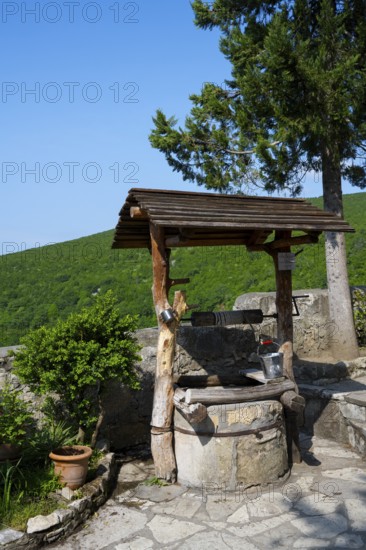 Rustic fountain with wooden roof surrounded by nature and plants in sunny weather, Motsameta