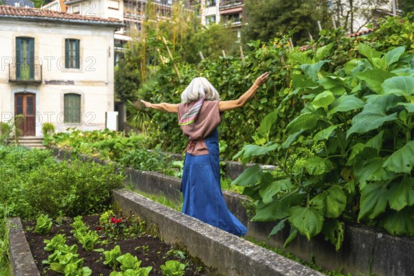 Senior woman with gray hair and scarf feeling freedom and happiness, walking with arms outstretched