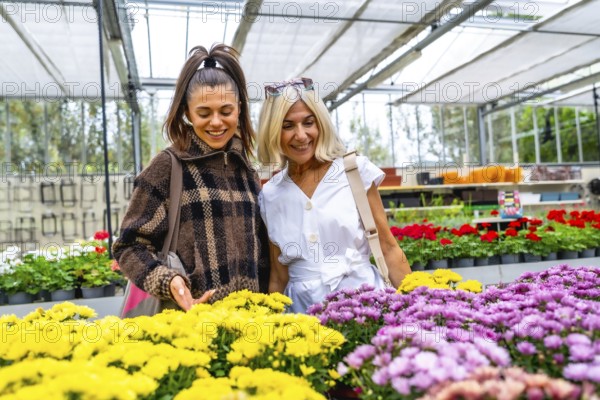 Happy mother and adult daughter enjoying choosing colorful blooming flowers together, bonding and