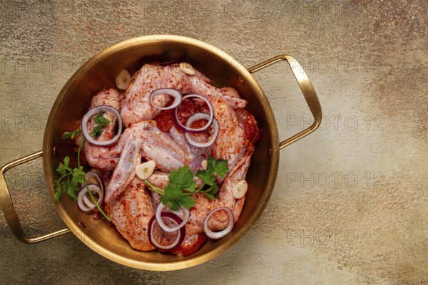 Chicken wings, in a brass saucepan, ready for cooking, grilling or baking, in a home kitchen, no