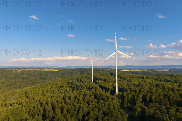 Green forests with several wind power plants under vivid blue sky with clouds, near Schorndorf,