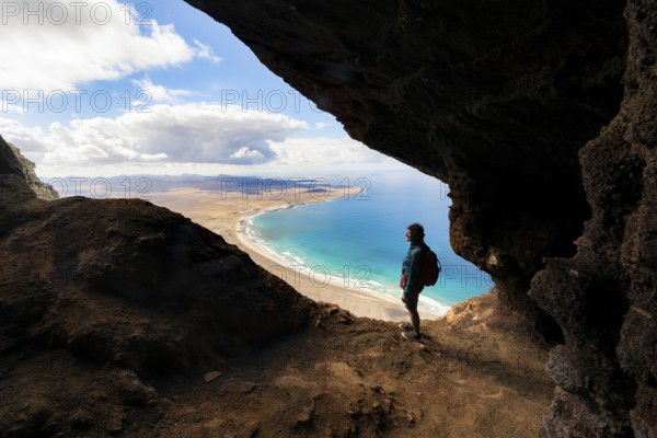 Tourist in the Cueva de las Cabras cave, old woman enjoying the view from the Risco de Famara