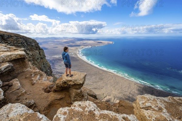Woman enjoying the view from the Risco de Famara cliffs on Famara beach, Playa de Famara with La