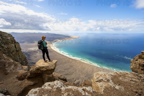 Young woman enjoying the view from the Risco de Famara cliffs to Famara beach, Playa de Famara with