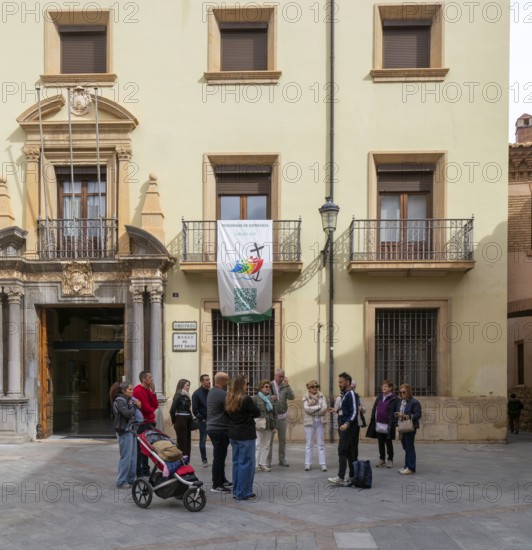 Tour guide and group of people outside museum of sacred art building, cathedral square, Teruel,