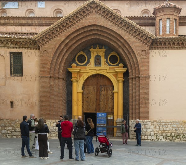 Tour guide and group of people outside Mudéjar door of cathedral church building, city centre of