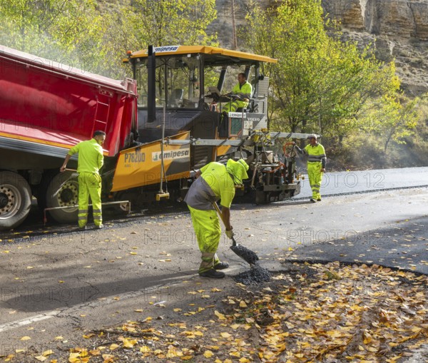 Asphalt road construction team of workers resurfacing tarmac in rural area, near Albarracin, Teruel