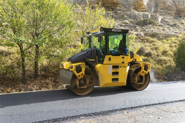BOMAG compactor machine asphalt road construction resurfacing tarmac in rural area, near