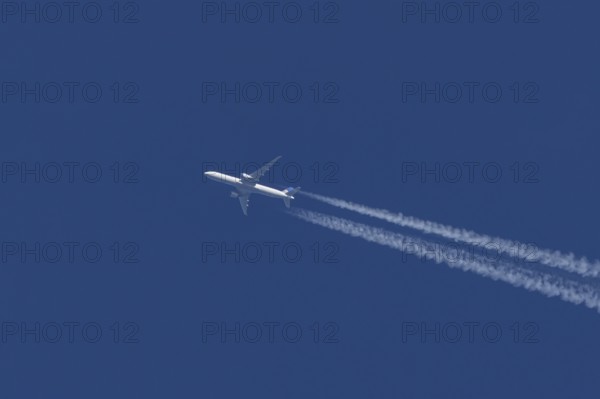 Boeing jet passenger aircraft of United airways airlines flying in a blue sky with contrails or