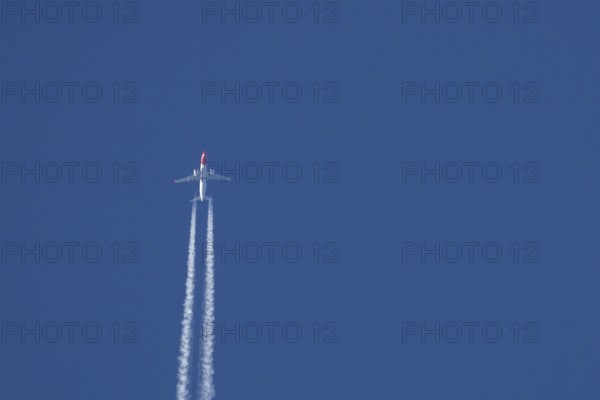 Boeing 737 jet passenger aircraft of Norwegian Air airlines flying in a blue sky with contrails or