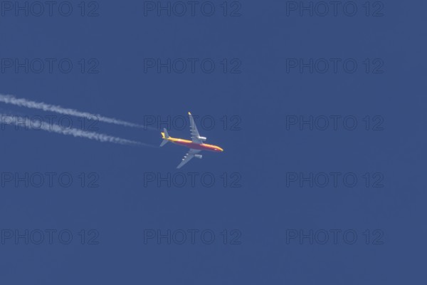 Boeing 767 jet cargo aircraft of DHL airlines flying in a blue sky with contrails or vapours trails