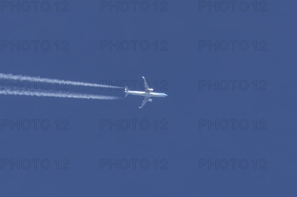 Jet passenger aircraft flying in a blue sky with contrails or vapour trails behind, England, United
