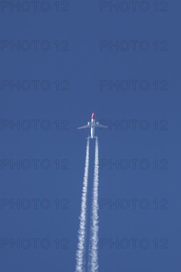 Boeing 737 jet passenger aircraft of Norwegian Air airlines flying in a blue sky with contrails or