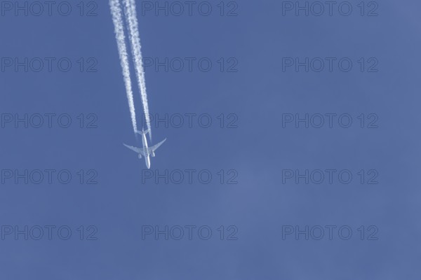 Boeing 777 jet passenger aircraft of Qatar airways airlines flying in a blue sky with contrails or