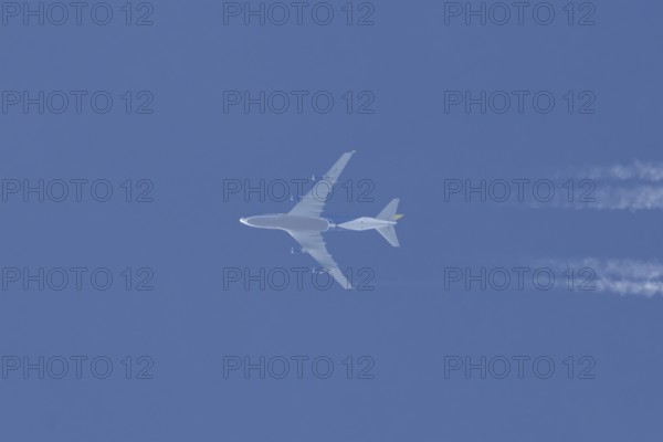 Boeing 747 jumbo jet cargo aircraft flying in a blue sky with contrails or vapour trails behind,