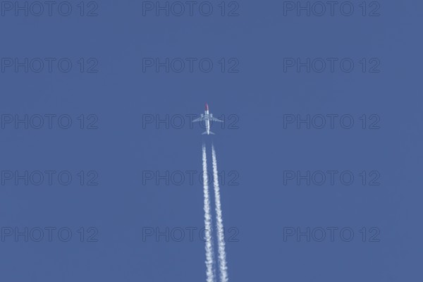 Boeing 737 jet passenger aircraft of Norwegian Air airlines flying in a blue sky with contrails or