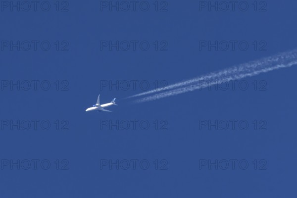 Boeing jet passenger aircraft of United airways airlines flying in a blue sky with contrails or