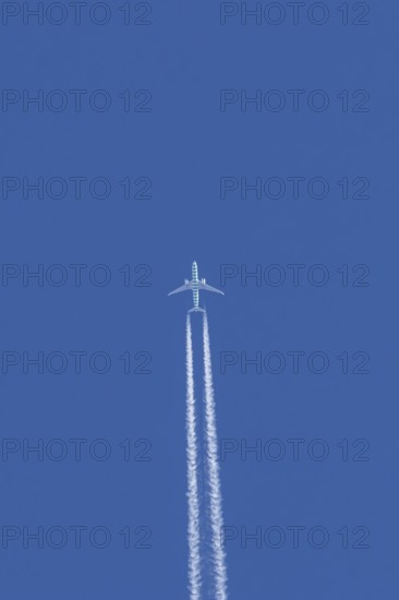 Boeing jet passenger aircraft flying in a blue sky with contrails or vapour trails behind, England,
