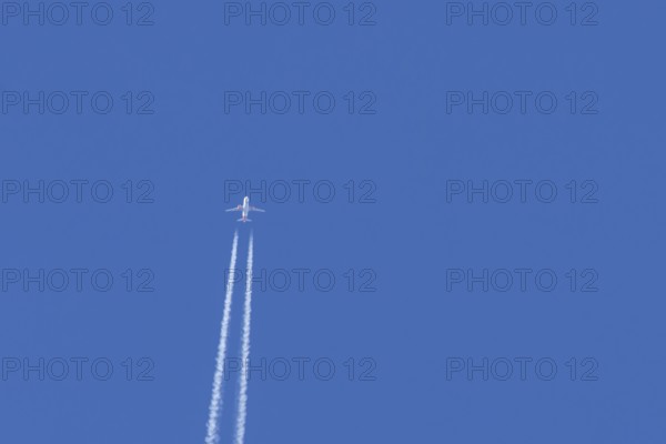 Airbus jet passenger aircraft of Easyjet airlines flying in a blue sky with contrails or vapour